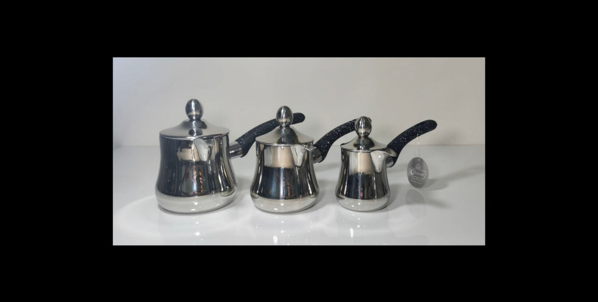 Three polished stainless steel teapots with black speckled handles and lids, arranged side by side on a white reflective surface against a light gray background.