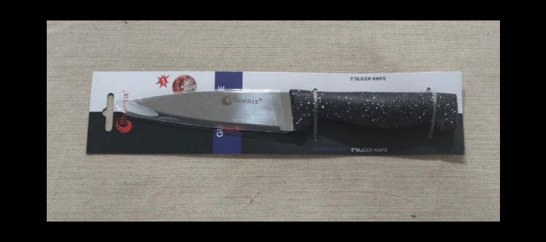 A small kitchen knife with a black speckled handle and a silver blade, still in its retail packaging, placed on a light beige textured surface.